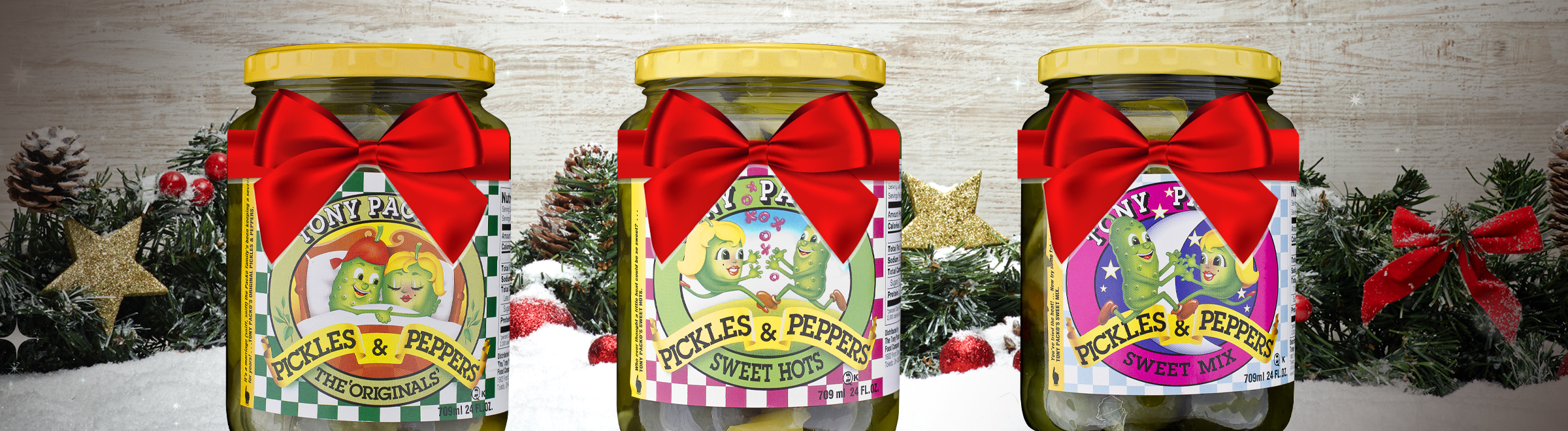 Holiday image of evergreen, holly and red bows with Packo's pickles jars and chili dog sauce in front.